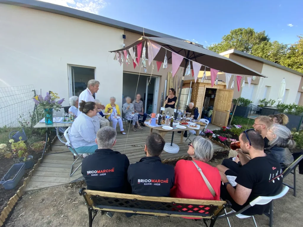 Moment convivial entre résidents et partenaires locaux sur la terrasse du village